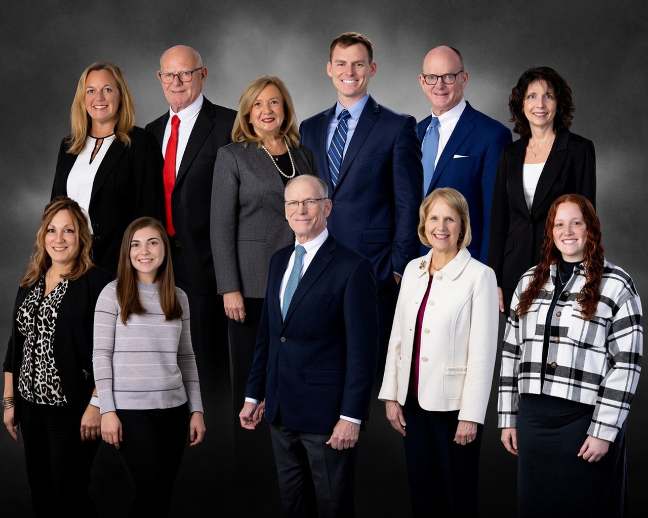 Group portrait of the Kerwin & Kerwin attorneys and staff in professional attire against a dark gray backdrop